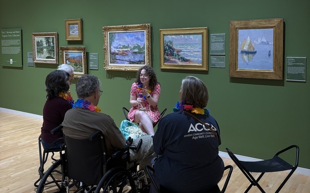 Mallory Lind leads a small group of adults with disabilities in a seated program in the galleries of the Georgia Museum of Art.